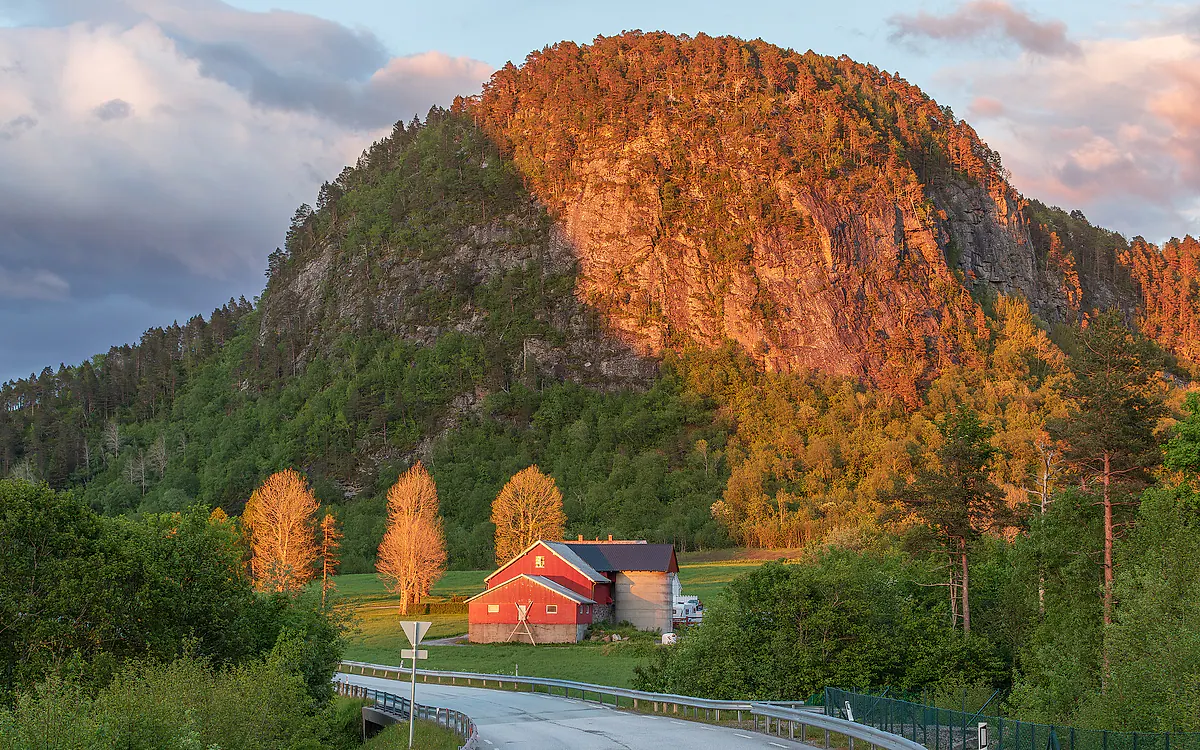 Røde hus under fjellene ved Romsdalsfjorden